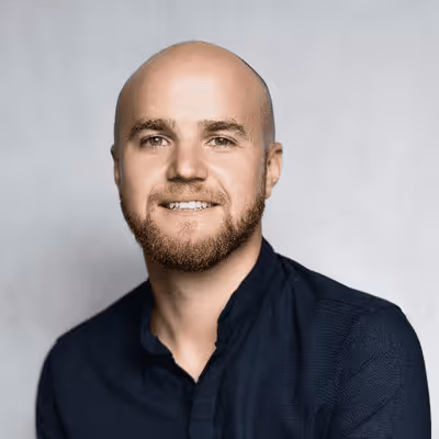 Smiling bald man with beard wearing a dark shirt.